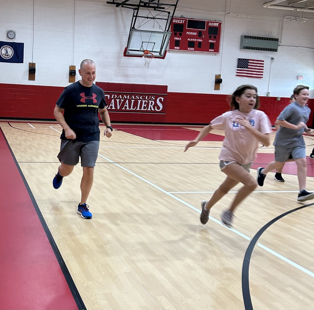 Man runs in a gym with students