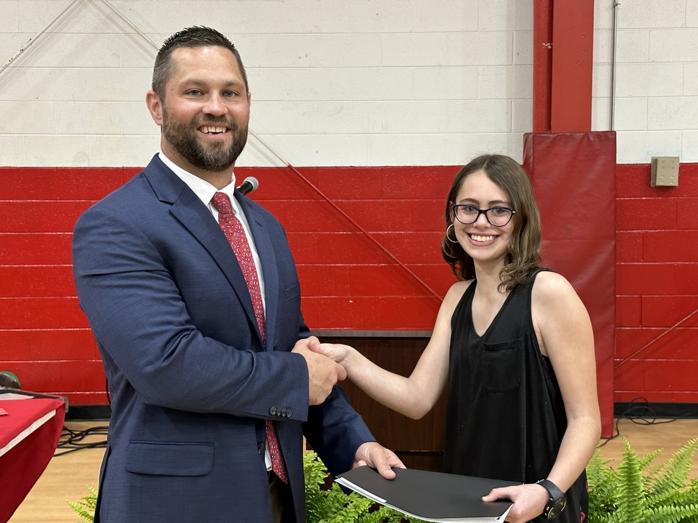 A man shakes a student's hand and gives her a certificate.
