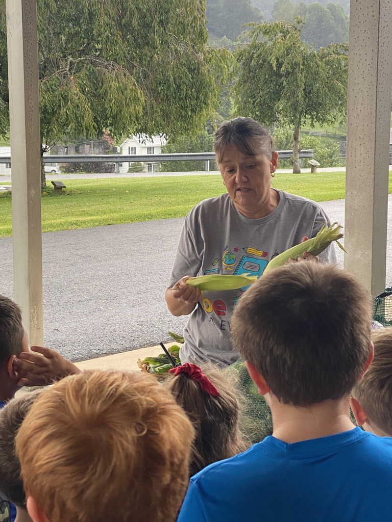 GES Cafeteria Manager Tammy Boyd shows students how to shuck corn.