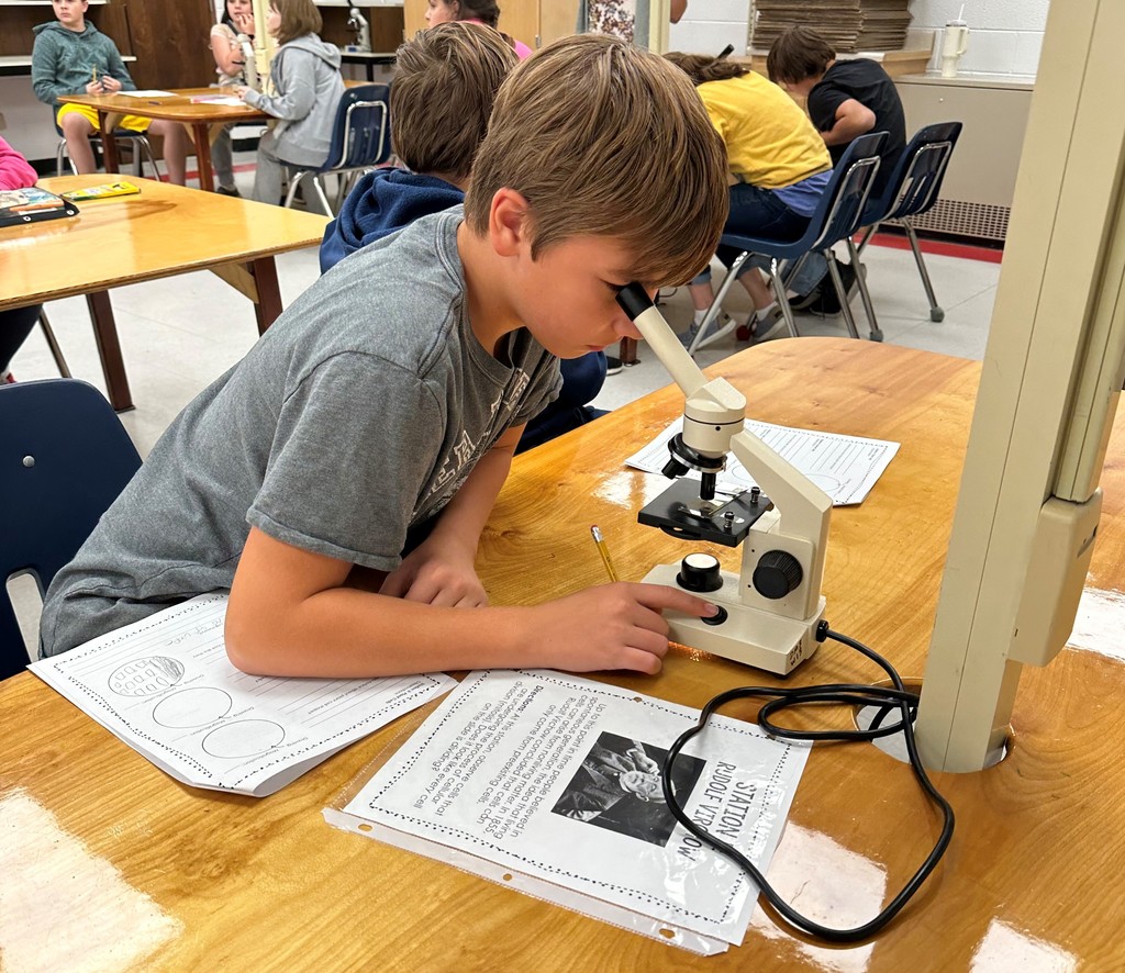 A student uses a microscope in a Science lab.